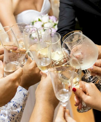 People clink champagne flutes and toast together at a celebration dinner, smiling as the glasses sparkle.