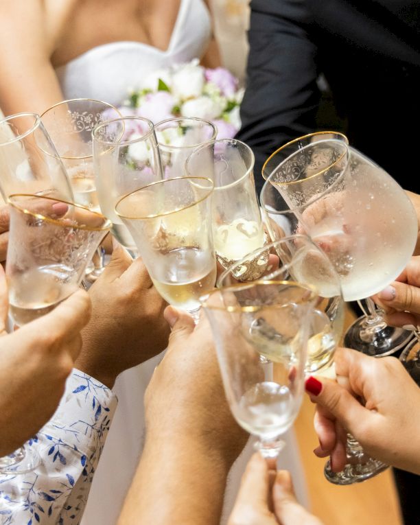 People clink champagne flutes and toast together at a celebration dinner, smiling as the glasses sparkle.